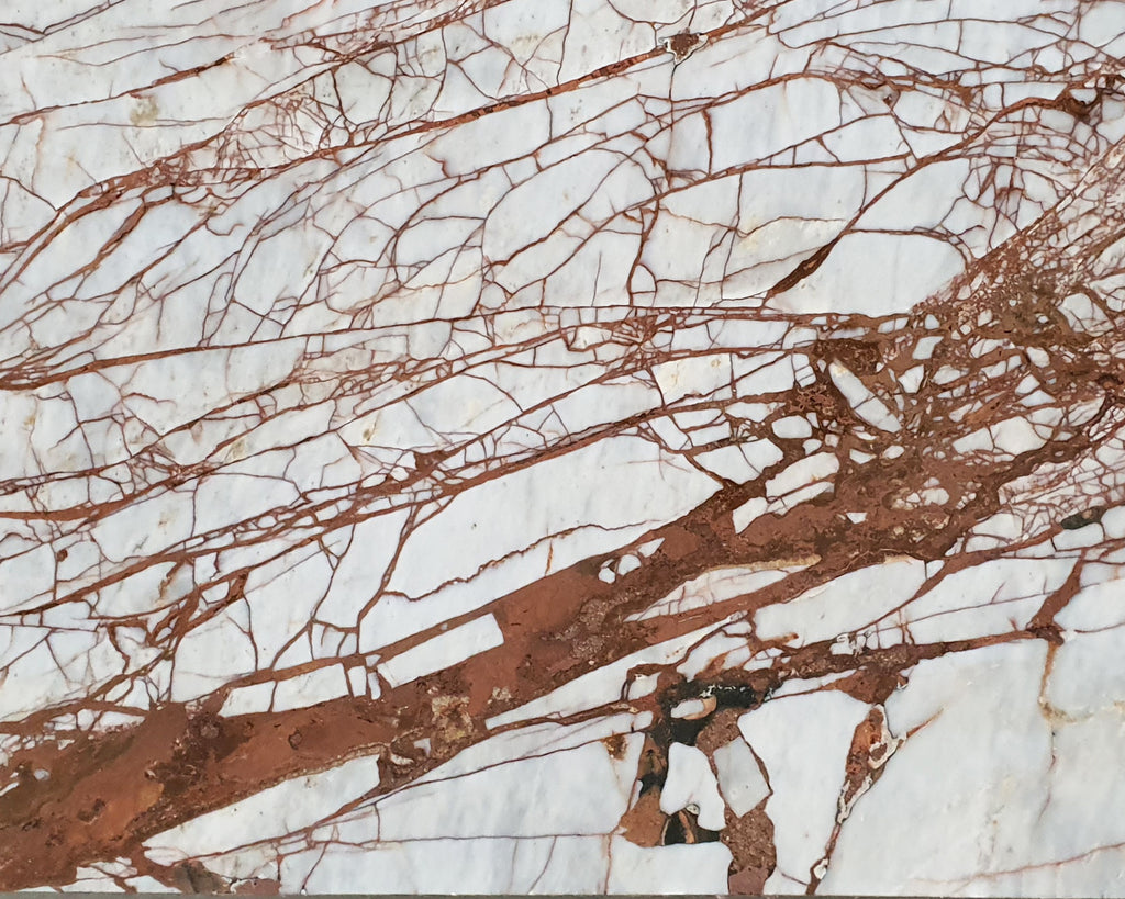 White marble with burnt red veining close up.